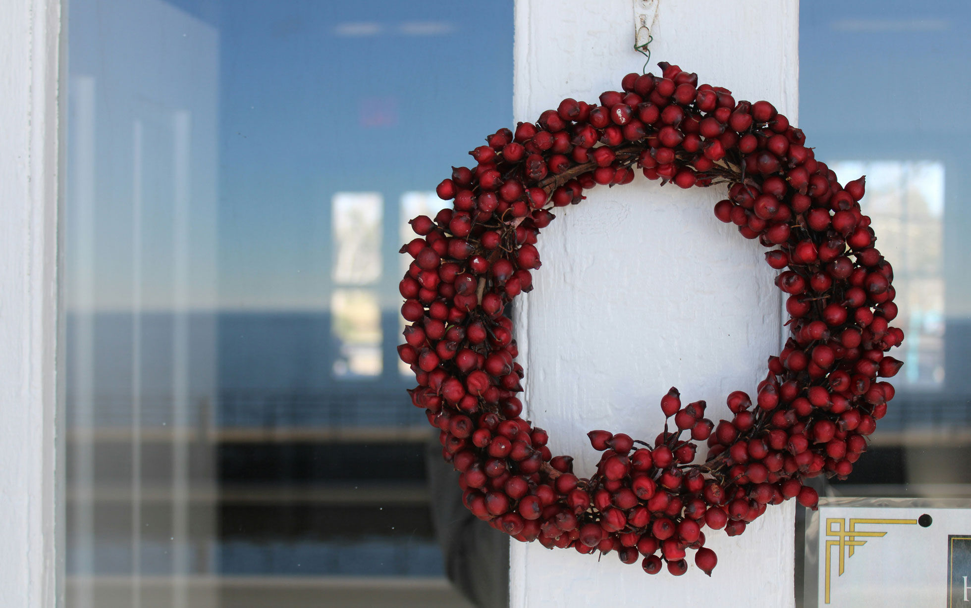 Weihnachtskranz mit roten Beeren auf weißer Tür