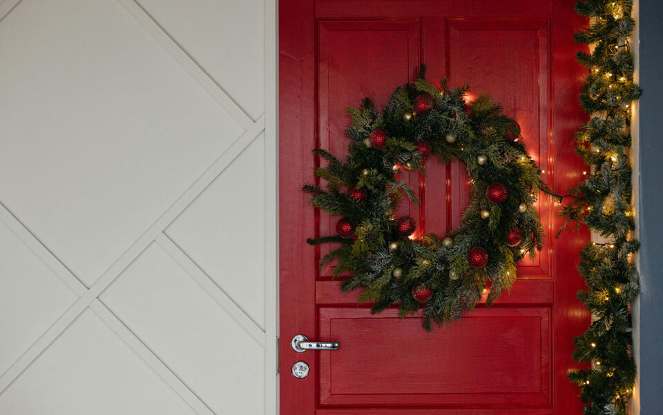 couronne de noel lumineuse sur porte d'entrée rouge