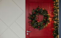 couronne de noel lumineuse sur porte d'entrée rouge